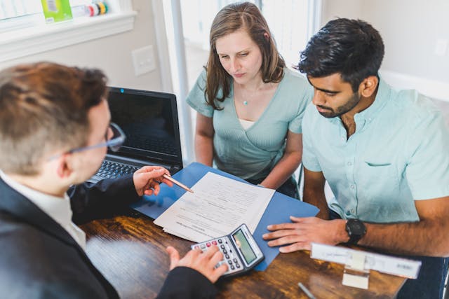 couple looking at a contract being presented to them by a man in a suit